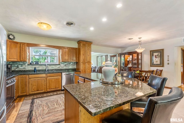 11 Shady Ln, Geneseo, IL 61254 - kitchen with stainless steel appliances, a sink, a kitchen island, backsplash, and a breakfast bar