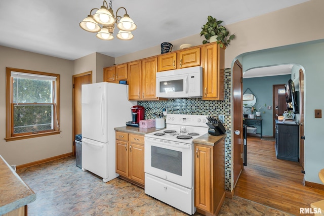 1519 W Columbia Ave, Davenport, IA 52804 - kitchen with white appliances, arched walkways, a chandelier, backsplash, and baseboards
