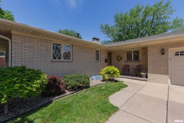 2737 28th Ave, Rock Island, IL 61201 - doorway to property with brick siding, a chimney, concrete driveway, and a garage