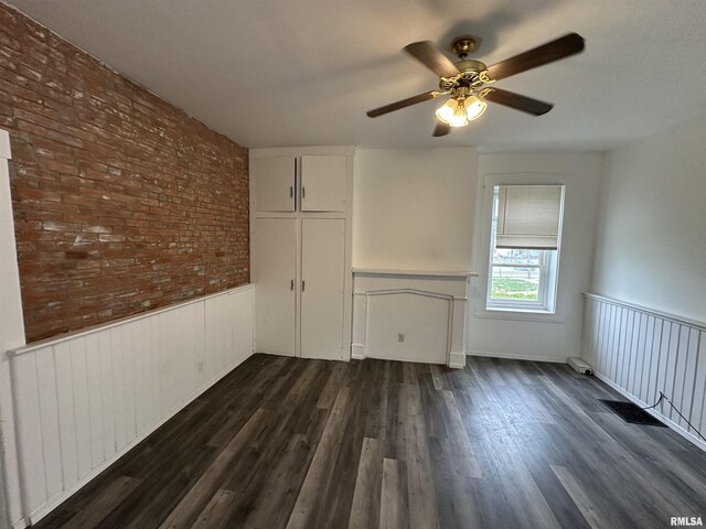 431 N 5th St, Quincy, IL 62301 - spare room featuring wainscoting, a ceiling fan, dark wood-style floors, and brick wall