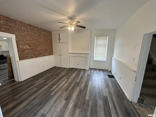 431 N 5th St, Quincy, IL 62301 - unfurnished living room with wainscoting, a ceiling fan, stairs, dark wood finished floors, and brick wall