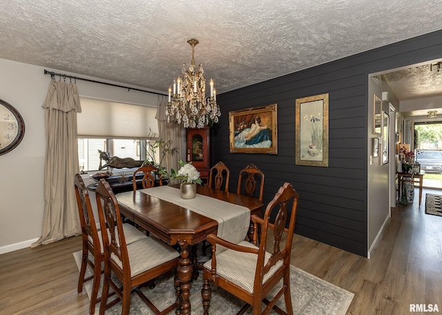 726 51st Ave Unit 20, East Moline, IL 61244 - dining space with baseboards, a chandelier, a textured ceiling, wood finished floors, and wooden walls