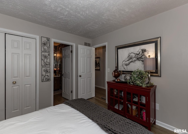 726 51st Ave Unit 20, East Moline, IL 61244 - bedroom featuring wood finished floors, a textured ceiling, baseboards, a closet, and ensuite bath