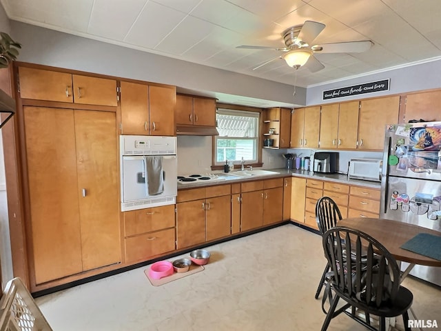 1324 Grandview Dr, Clinton, IA 52732 - kitchen featuring white appliances, a sink, light floors, brown cabinetry, and a ceiling fan