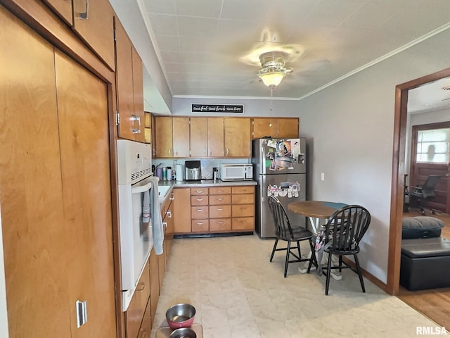 1324 Grandview Dr, Clinton, IA 52732 - kitchen featuring white appliances, ceiling fan, brown cabinets, crown molding, and baseboards