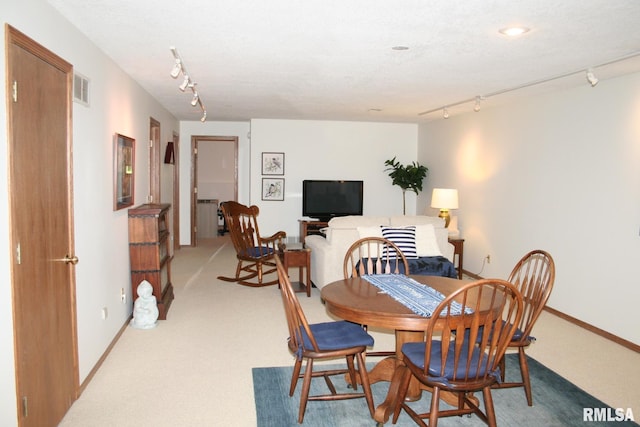 3996 Partridge Cir, Bettendorf, IA 52722 - dining room featuring rail lighting, light colored carpet, and baseboards