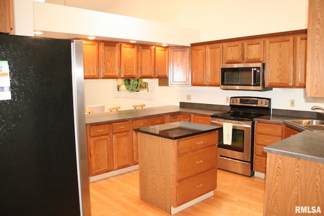 3996 Partridge Cir, Bettendorf, IA 52722 - kitchen featuring stainless steel appliances, a sink, dark countertops, light wood-style floors, and a kitchen island