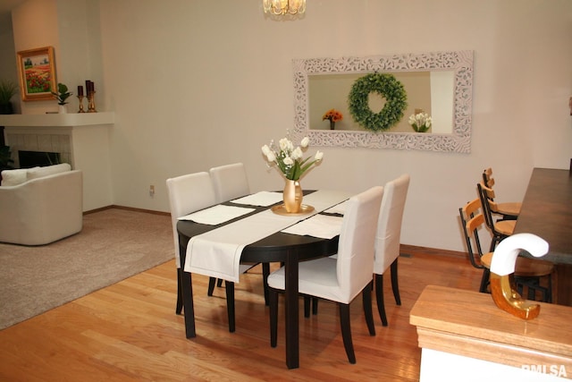 3996 Partridge Cir, Bettendorf, IA 52722 - dining area featuring light wood-type flooring, baseboards, a fireplace, and a chandelier
