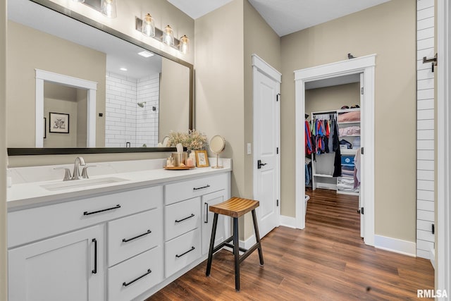 6997 Matthews Pass, Bettendorf, IA 52722 - full bathroom with vanity, a tile shower, wood finished floors, a spacious closet, and baseboards