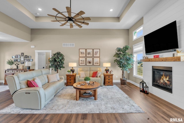 6997 Matthews Pass, Bettendorf, IA 52722 - living room featuring a high ceiling, ceiling fan, a large fireplace, wood finished floors, and baseboards
