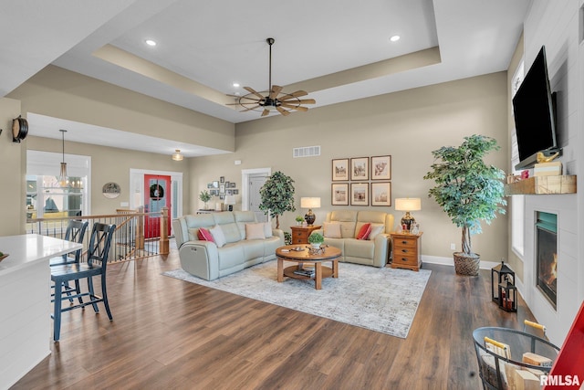 6997 Matthews Pass, Bettendorf, IA 52722 - living room featuring ceiling fan, a tray ceiling, a large fireplace, dark wood-type flooring, and recessed lighting