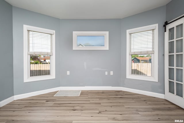 1637 24th Ave, Moline, IL 61265 - empty room with plenty of natural light, light wood finished floors, a barn door, and baseboards
