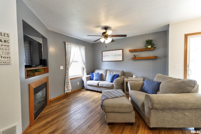 414 11th Avenue A Court, Silvis, IL 61282 - living room featuring wood finished floors, a ceiling fan, a glass covered fireplace, and baseboards