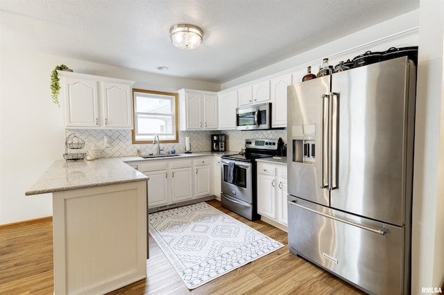 414 11th Avenue A Court, Silvis, IL 61282 - kitchen with appliances with stainless steel finishes, a peninsula, a sink, light wood-style floors, and decorative backsplash