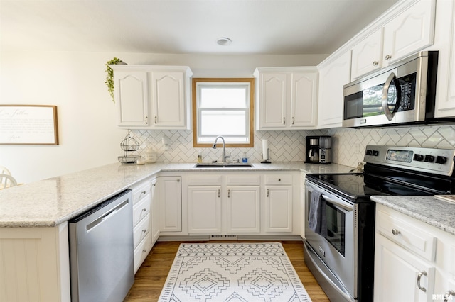 414 11th Avenue A Court, Silvis, IL 61282 - kitchen with stainless steel appliances, a sink, a peninsula, white cabinetry, and decorative backsplash