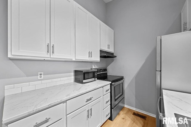 4015 Lillie Ave Unit 106, Davenport, IA 52806 - kitchen featuring appliances with stainless steel finishes, under cabinet range hood, white cabinetry, light wood-style flooring, and light stone countertops