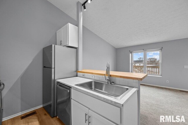 4015 Lillie Ave Unit 106, Davenport, IA 52806 - kitchen with a textured ceiling, dishwasher, a sink, a peninsula, and butcher block counters
