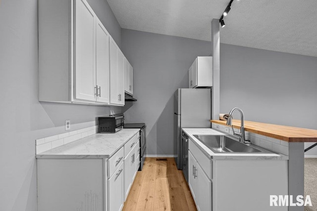 4015 Lillie Ave Unit 106, Davenport, IA 52806 - kitchen featuring appliances with stainless steel finishes, under cabinet range hood, a sink, a peninsula, and white cabinets