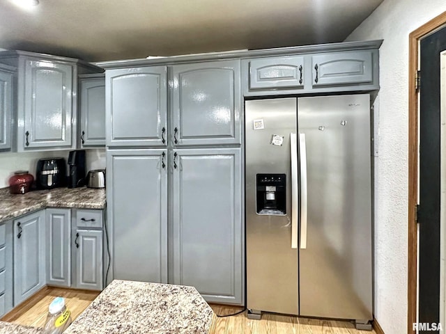 52 Chickasaw St, Mcclure, IL 62957 - kitchen with stainless steel fridge with ice dispenser, gray cabinets, light wood finished floors, and stone counters