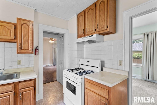 546 21st Ave, Moline, IL 61265 - kitchen with white gas range oven, under cabinet range hood, a sink, light countertops, and tasteful backsplash