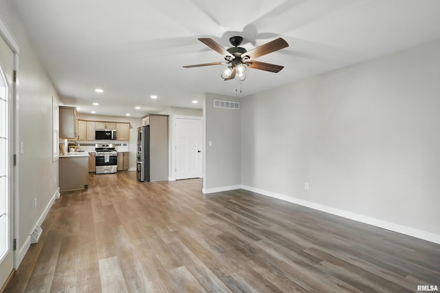 3610 Tam-O-Shanter Dr, Bettendorf, IA 52722 - unfurnished living room with recessed lighting, a ceiling fan, baseboards, wood finished floors, and a sink
