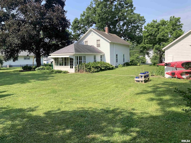 706 N Main St, Port Byron, IL 61275 - rear view of house featuring a lawn, a chimney, and a sunroom