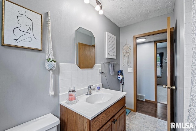 3115 W 63rd St, Davenport, IA 52806 - bathroom featuring toilet, vanity, backsplash, and a textured ceiling