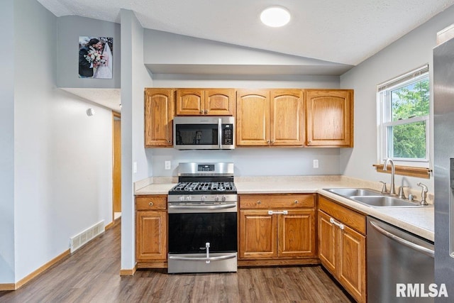 3115 W 63rd St, Davenport, IA 52806 - kitchen featuring appliances with stainless steel finishes, a sink, vaulted ceiling, dark wood-style flooring, and light countertops