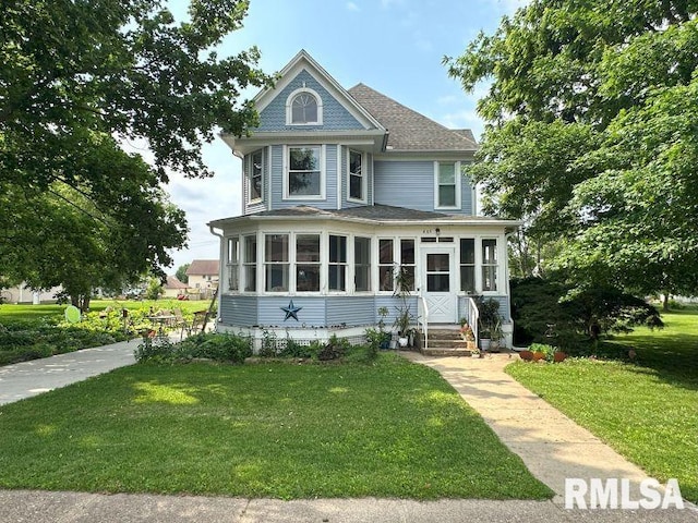 605 Fulton St, Grand Mound, IA 52751 - victorian house with a front lawn, roof with shingles, and a sunroom