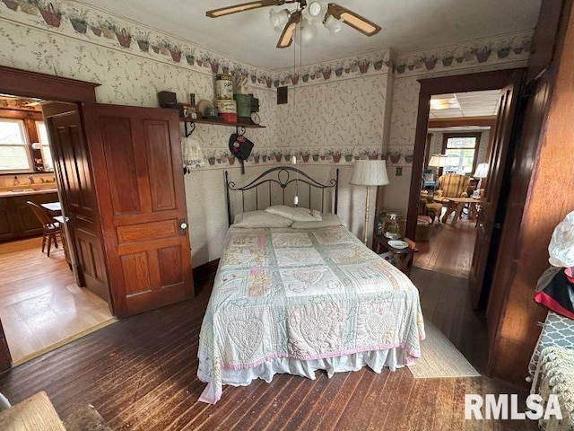 605 Fulton St, Grand Mound, IA 52751 - bedroom with wallpapered walls, hardwood / wood-style flooring, a wainscoted wall, and a ceiling fan