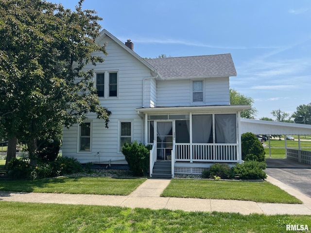 246 Willard St, Kewanee, IL 61443 - view of front of house with a front yard, an attached carport, a chimney, and a sunroom