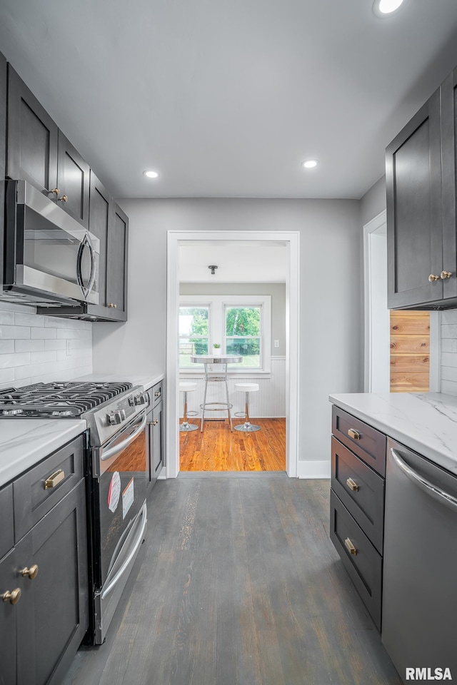 4418 11th St, East Moline, IL 61244 - kitchen with appliances with stainless steel finishes, dark wood-type flooring, tasteful backsplash, light stone countertops, and recessed lighting
