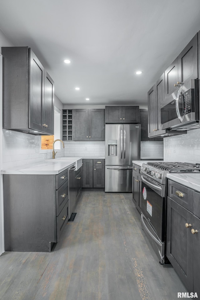 4418 11th St, East Moline, IL 61244 - kitchen featuring stainless steel appliances, decorative backsplash, dark wood-type flooring, light countertops, and recessed lighting