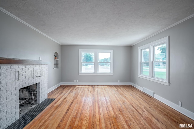 4418 11th St, East Moline, IL 61244 - unfurnished living room with light wood-style flooring, a textured ceiling, a fireplace, baseboards, and ornamental molding