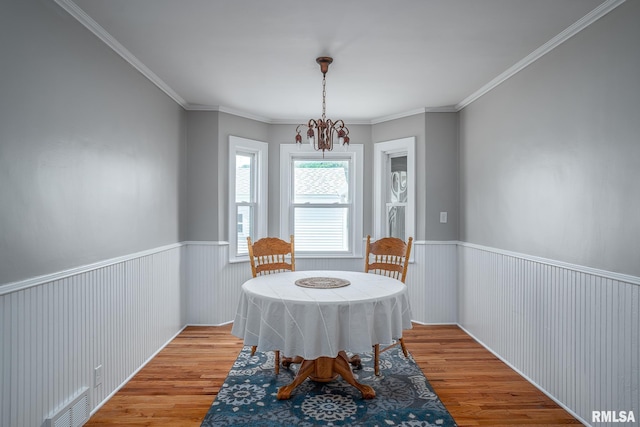 4418 11th St, East Moline, IL 61244 - dining area featuring wood finished floors, a chandelier, wainscoting, and ornamental molding