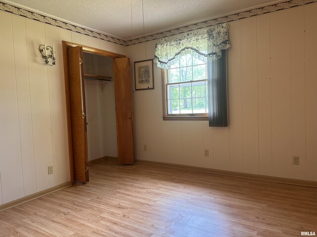 690 Railroad St, Tamms, IL 62988 - unfurnished bedroom with light wood-style flooring, a textured ceiling, a closet, and a decorative wall