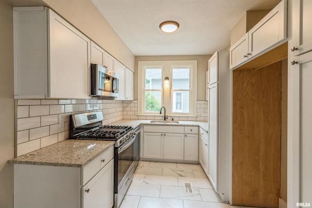 2037 18th St Unit B, Moline, IL 61265 - kitchen featuring appliances with stainless steel finishes, light marble finish floors, light stone counters, a sink, and decorative backsplash