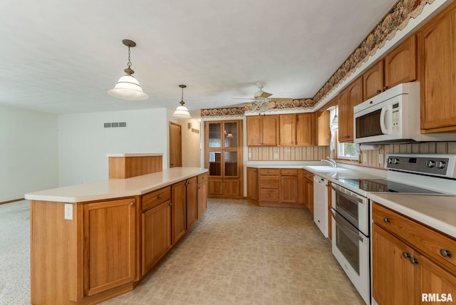 605 SW 5th Ave, Aledo, IL 61231 - kitchen featuring white appliances, a sink, a kitchen island, light countertops, and brown cabinets