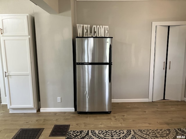 136 W Mill St, Kewanee, IL 61443 - kitchen with freestanding refrigerator, light wood-style floors, baseboards, and white cabinetry