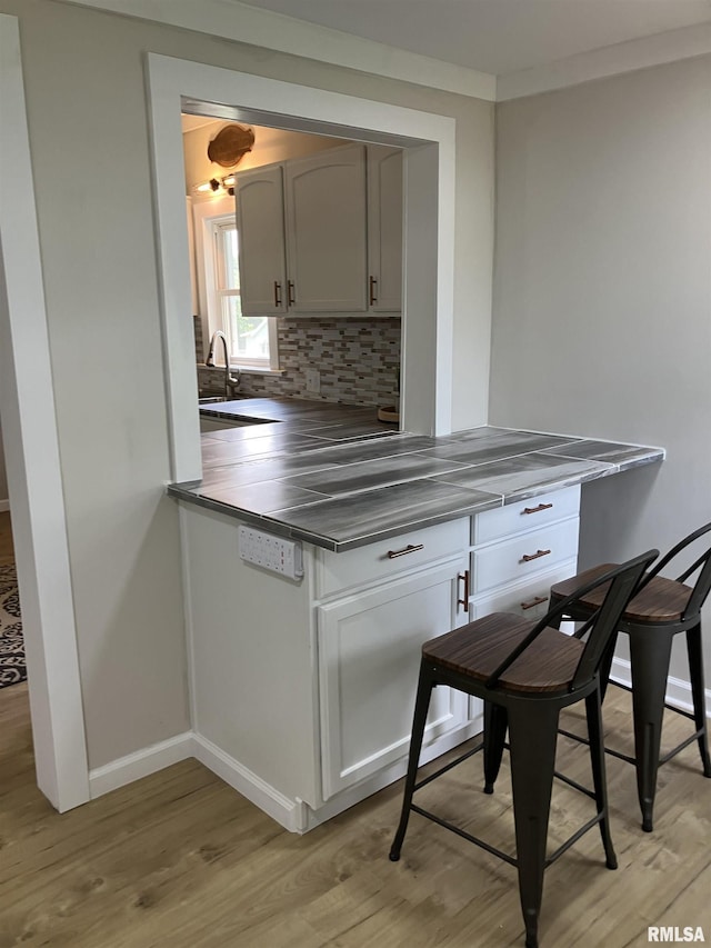 136 W Mill St, Kewanee, IL 61443 - kitchen with light wood-style flooring, backsplash, baseboards, a sink, and dark countertops