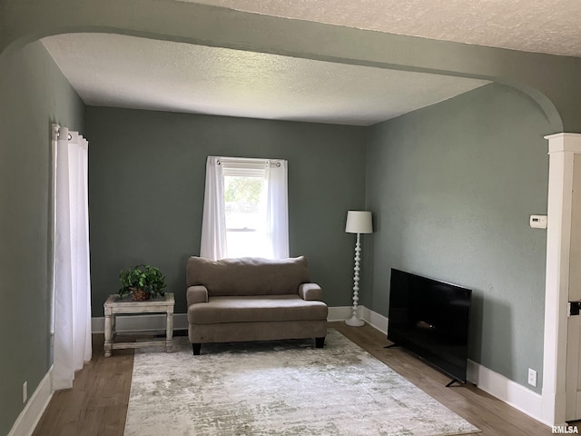 136 W Mill St, Kewanee, IL 61443 - living area featuring arched walkways, wood finished floors, baseboards, and a textured ceiling