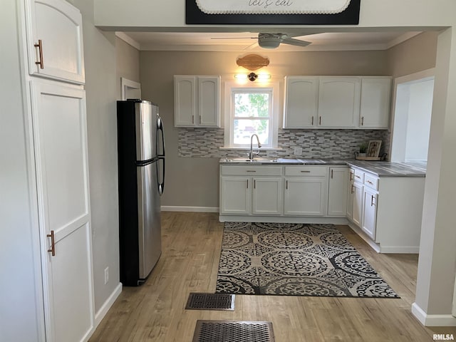 136 W Mill St, Kewanee, IL 61443 - kitchen with freestanding refrigerator, a sink, backsplash, white cabinetry, and light wood-type flooring