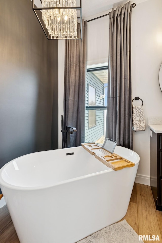 18101 271st St, Long Grove, IA 52756 - bathroom with vanity, wood finished floors, a soaking tub, a chandelier, and baseboards