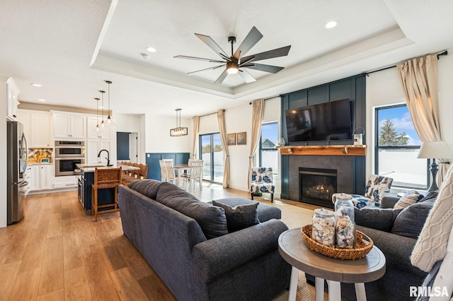 18101 271st St, Long Grove, IA 52756 - living area featuring a tray ceiling, light wood-style flooring, a ceiling fan, healthy amount of natural light, and recessed lighting