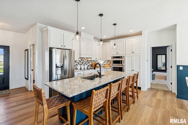 18101 271st St, Long Grove, IA 52756 - kitchen featuring appliances with stainless steel finishes, light wood-style flooring, a sink, white cabinets, and a kitchen bar