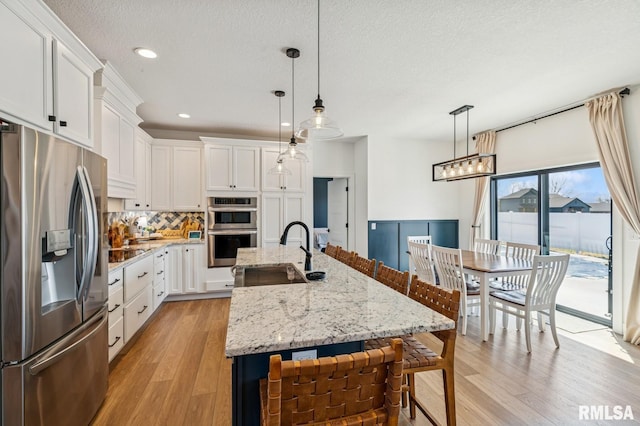 18101 271st St, Long Grove, IA 52756 - kitchen featuring stainless steel appliances, a sink, light wood-style floors, tasteful backsplash, and a breakfast bar