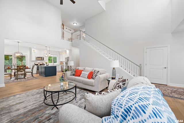 1100 Wild W Dr, Le Claire, IA 52753 - living room with a high ceiling, light wood-style flooring, stairs, and a ceiling fan