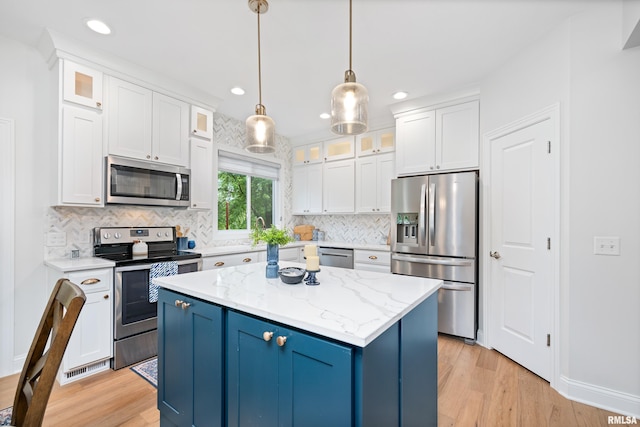 1100 Wild W Dr, Le Claire, IA 52753 - kitchen with appliances with stainless steel finishes, light wood-style flooring, a center island, tasteful backsplash, and white cabinets