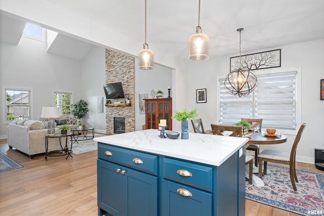 1100 Wild W Dr, Le Claire, IA 52753 - kitchen featuring open floor plan, a chandelier, light wood-style flooring, blue cabinets, and a skylight