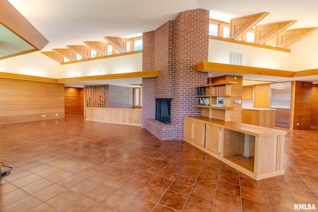 7 Sharon Ln, Fulton, IL 61252 - unfurnished living room featuring high vaulted ceiling, wood walls, tile patterned flooring, and a fireplace